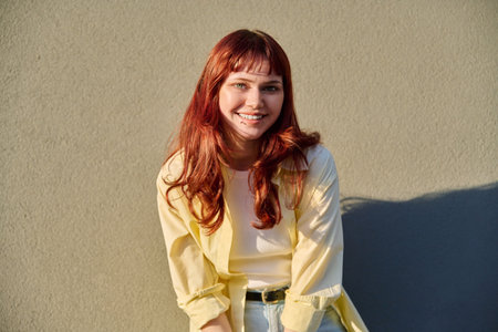Happy young hipster female with red hair facial piercing, gray wall backgroundの写真素材
