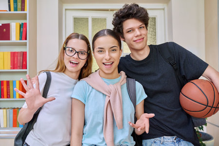 Three cheerful teenagers students looking at camera inside school campusの写真素材