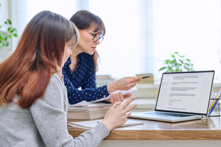 Female teacher mentor teaching young teenage girl student using laptop computer