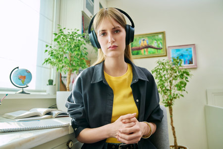 Teenage student girl in headphones having video conference, at home, webcam view