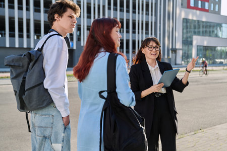Woman agent teacher social worker working with college students using digital tablet outdoorの写真素材