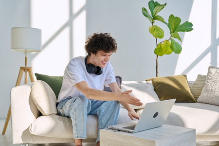 Young man using laptop for video call, online chat conference sitting at homeの写真素材