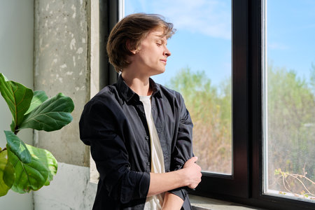 Handsome young smiling guy looking out the windowの写真素材