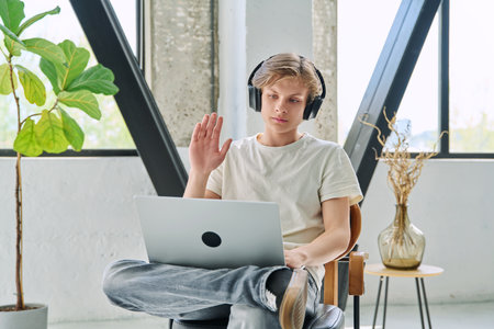 Teenage boy with headphones using laptop for video conference, online meetingの写真素材