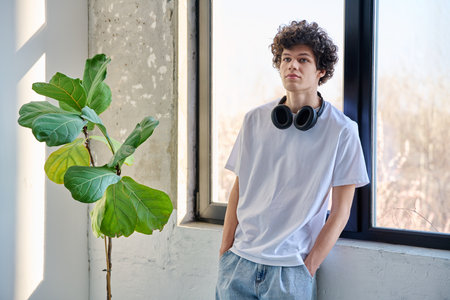 Portrait handsome young man with headphones, near window, copy spaceの写真素材