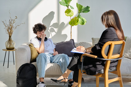 Sad young male patient in therapy session in psychologist counselor officeの写真素材