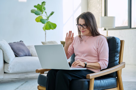 Middle aged woman working remotely, video conference, using laptopの写真素材