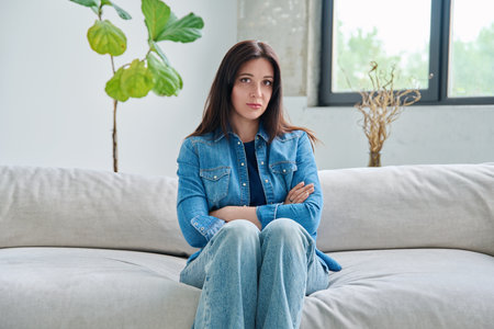 Portrait of beautiful young brunette woman sitting on sofa in living roomの写真素材