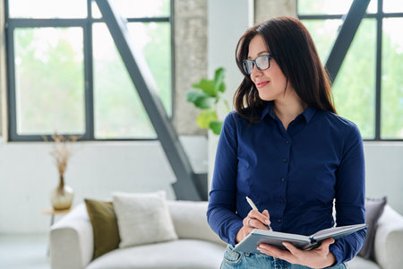 Portrait of smiling business woman with notebook in office with couchの写真素材