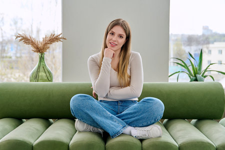 Portrait of relaxed beautiful young woman sitting at home on sofaの写真素材