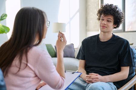 Young male patient talking to professional psychologist social worker counselorの写真素材