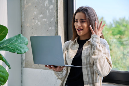 Young teenage girl using laptop for video chat conference standing at homeの写真素材