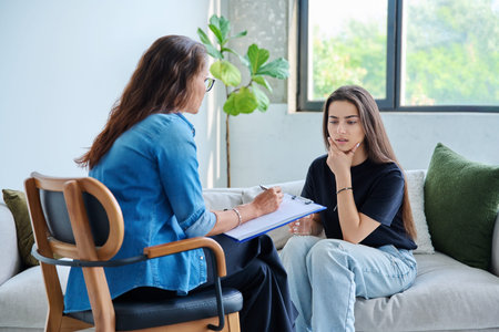 Sad teenage girl student talking with social psychologist, therapist, counselorの写真素材