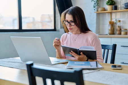 Middle-aged serious woman working at computer laptop in home officeの写真素材