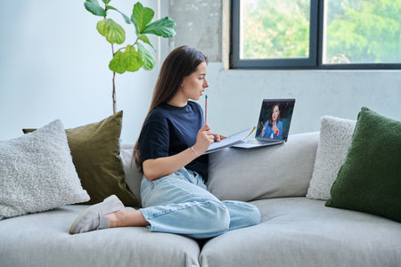 Teenage girl student having online lesson, watching webinar, at homeの写真素材