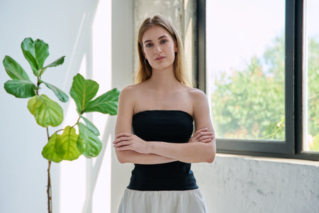 Portrait of serious young woman looking at camera with crossed arms in homeの写真素材