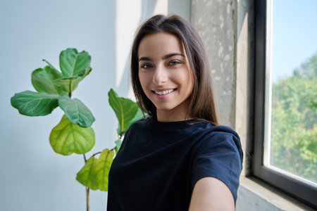 Close-up selfie portrait of teenage female looking at web cameraの写真素材