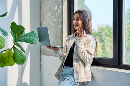 Young teenage girl using laptop for video chat conference standing at homeの写真素材