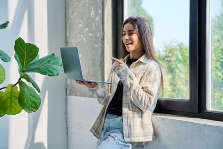 Young teenage girl using laptop for video chat conference standing at homeの写真素材