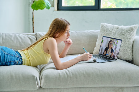 Teenage girl student having online lesson, watching webinar, at home