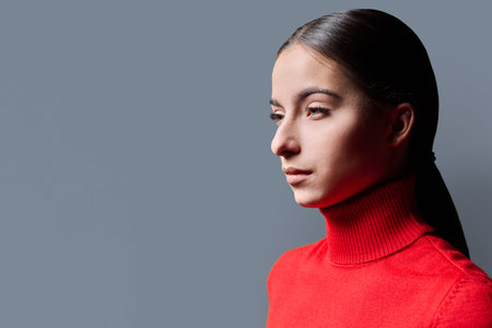 Profile portrait of young serious woman on gray background