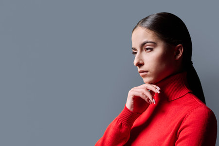 Profile portrait of young serious woman on gray backgroundの写真素材
