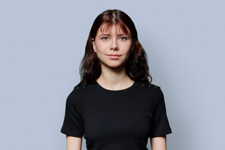 Portrait of smiling teenage girl with long hair on gray background