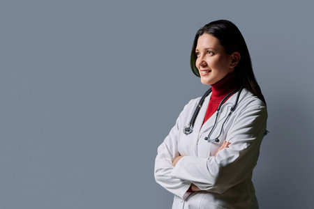 Profile view of positive female doctor with stethoscope on gray backgroundの写真素材