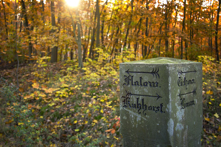 Historical mile marker or milepost with old german inscription in the autumn forest, was seen in Brandenburg, Havelland, Germanyの写真素材