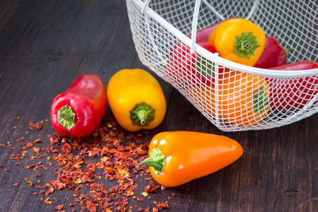 Fresh sweet (paprika) peppers on the wooden table with little metal basket and  spicy chilli.の写真素材