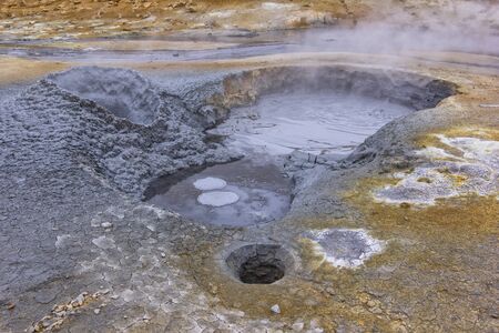View to a mudpot, or mud pool. It is a sort of acidic hot spring, or fumarole, with limited water. It usually takes the form of a pool of bubbling mud. Iceland.の写真素材