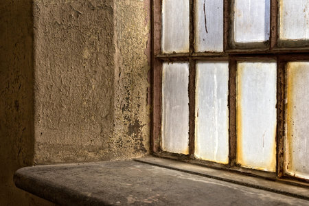 Detail of a window in an old factory building with warm light.