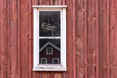 A little window in front of a typival scandinavian building with falu red. Was seen in Sweden.の写真素材
