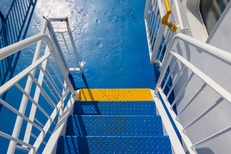 A yellow step on a blue staircase. Detail of a promenade deck on a ship. The colour contrast of blue...