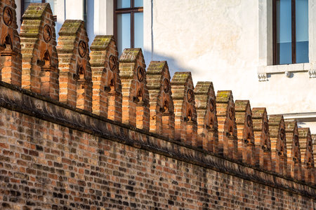 View of an old wall of red bricks, with gothic ornaments. This architectural detail was seen in...