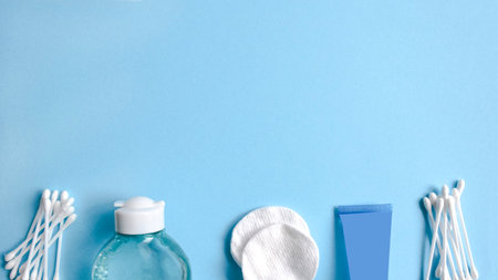 Set of cosmetic products on blue color background. Cotton pads, cotton sticks, bottle, makeup...