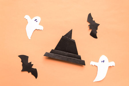 Happy Halloween holiday concept. Halloween decorations, bats, spooky and origami witch hat on beige...