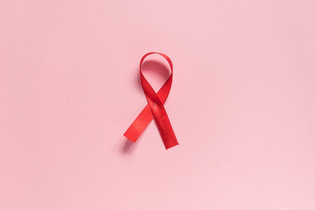 Red ribbon on a pink background. The concept of medicine and human health care. World breast cancer awareness and prevention day. Flat lay, copy spaceの写真素材