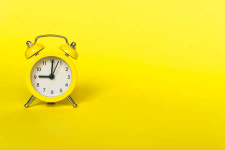 Ringing twin bell vintage classic alarm clock isolated on yellow background. Rest hours time of life good morning night wake up awake concept. Flat lay top view copy spaceの写真素材
