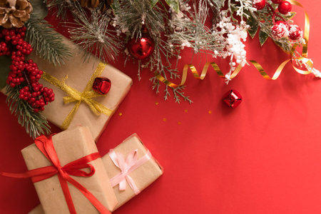 Beautiful Christmas composition with gift box tied with a ribbon, presents and fir branches on red...