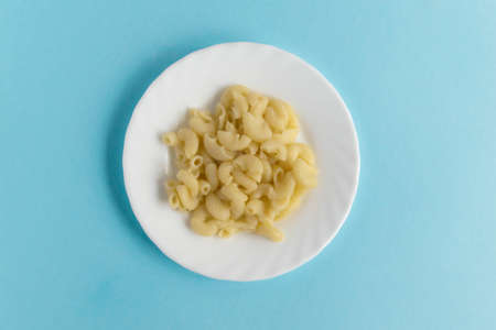Funny Breakfast, lunch or dinner for children in the form of a bull's face made of pasta, sausage, bacon, olives and fresh tomatoes on a blue background. Instruction how to make creative food art breakfast for kids. Step 1. Top view.の写真素材