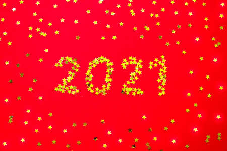 Small golden stars in the form of number 2021 on red background. Christmas, Xmas and New Year celebration, holiday party decoration concept. Flat lay, top view style.の写真素材