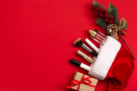 Flat lay composition with makeup products and Christmas decor on red paper background. Xmas, happy new year 2021, female wishes concept. Top view, copy spaceの写真素材