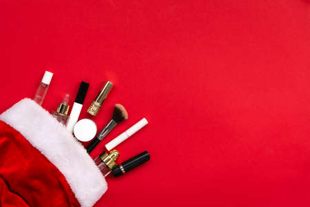 Flat lay composition with makeup products and Christmas decor on red paper background. Xmas, happy new year 2021, female wishes concept. Top view, copy spaceの写真素材