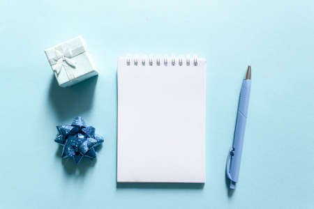 Notebook and pen on a blue background, spiral notepad with gift on a table. space for your text, greetings, top view, flat layの写真素材
