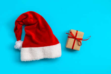 Santa Claus hat and gift box on light blue background. Christmas and New Year concept. flat layの写真素材