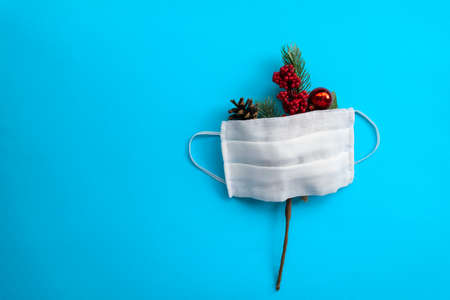 Single fir branches and medical mask on blue background. Christmas minimalism. Flat lay with copy space.の写真素材