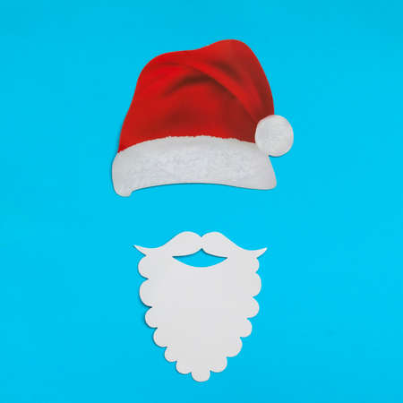Santa Claus hat and beard on light blue background. Christmas and New Year concept. flat layの写真素材