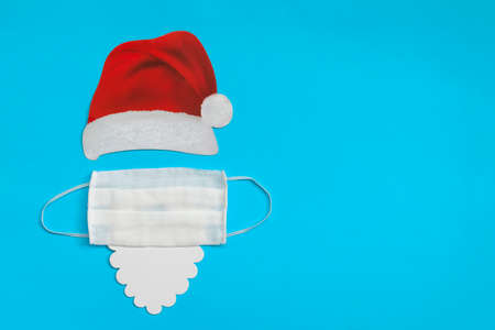 Santa Claus hat and beard with medical mask on light blue background. Christmas and New Year concept. flat lay with space for textの写真素材