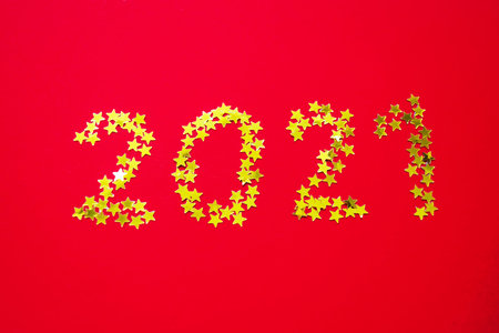 Small golden stars in the form of number 2021 on red background. Christmas, Xmas and New Year...